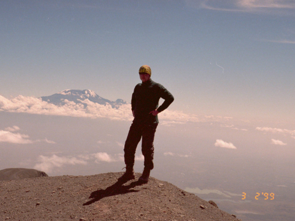 Já na vrcholu v pozadí Kilimanjaro.